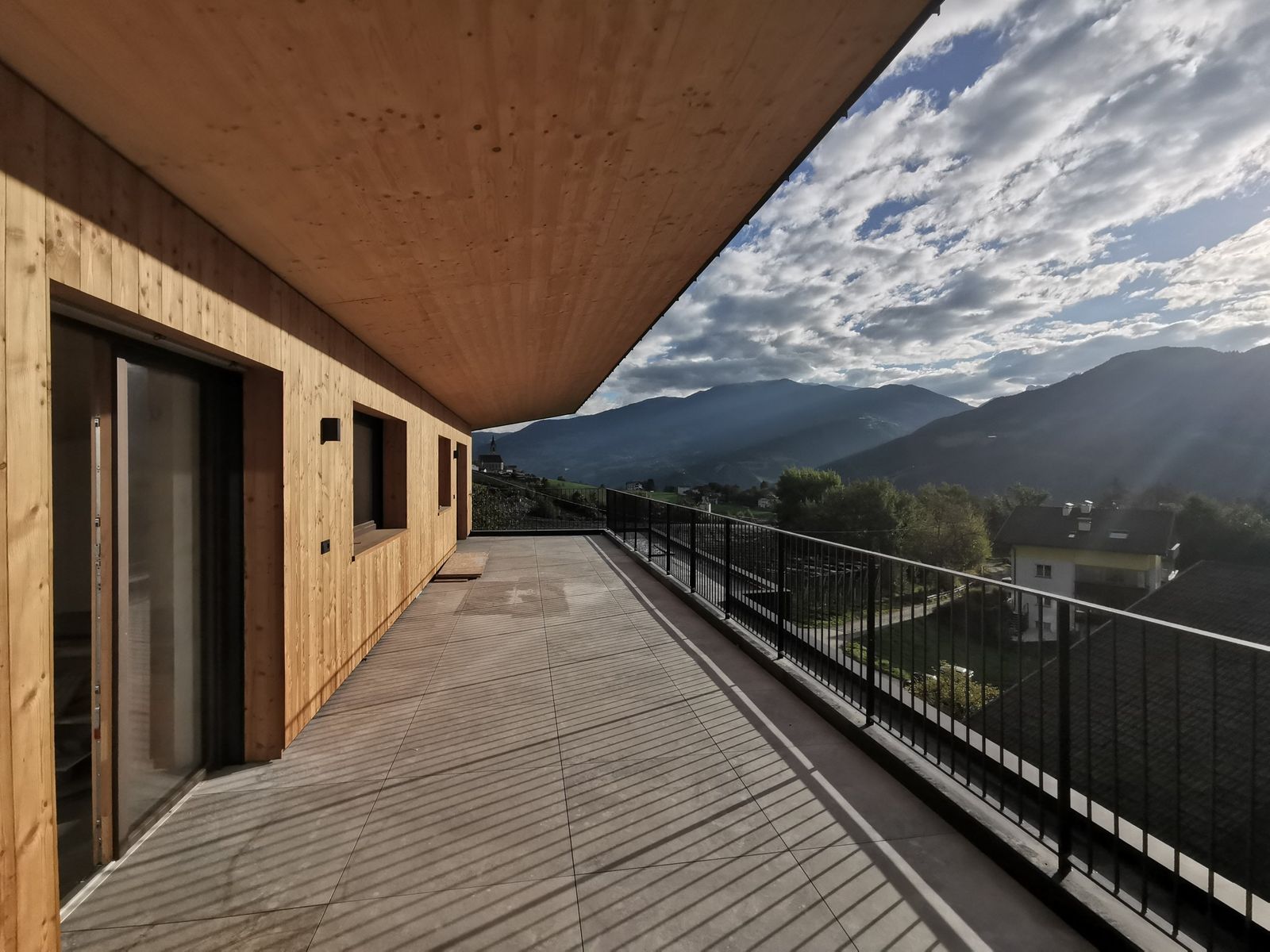 Überdachte Terrasse mit Holzfassade und Blick über Feldthurns ins Tal