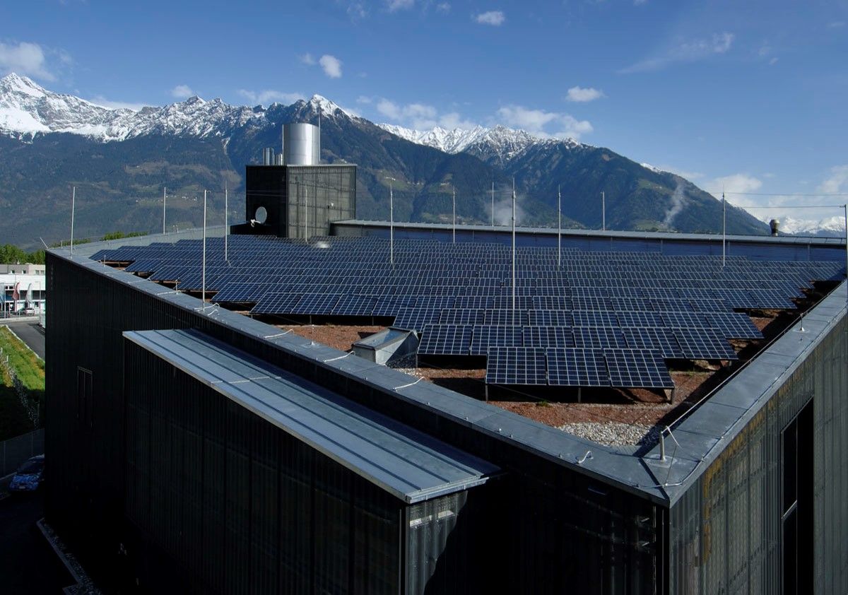 Heizkraftwerk Zipperle in Meran mit Photovoltaik auf dem Dach vor den Bergen